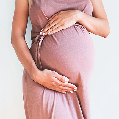 Pregnant woman holds hands on belly